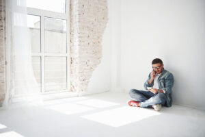 мужчина сидит на полу в пустой квартире