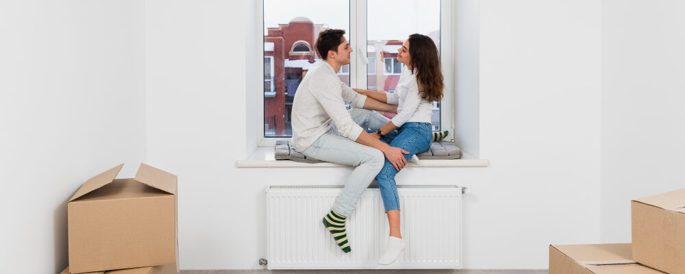молодая пара сидит на подоконнике в новой квартире